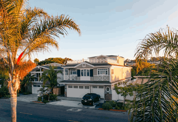 Two-story coastal-style home with palm trees and attached garage